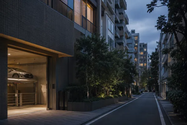 A quiet high-end residential street in central Tokyo at dusk, with a mechanical parking lift at street level